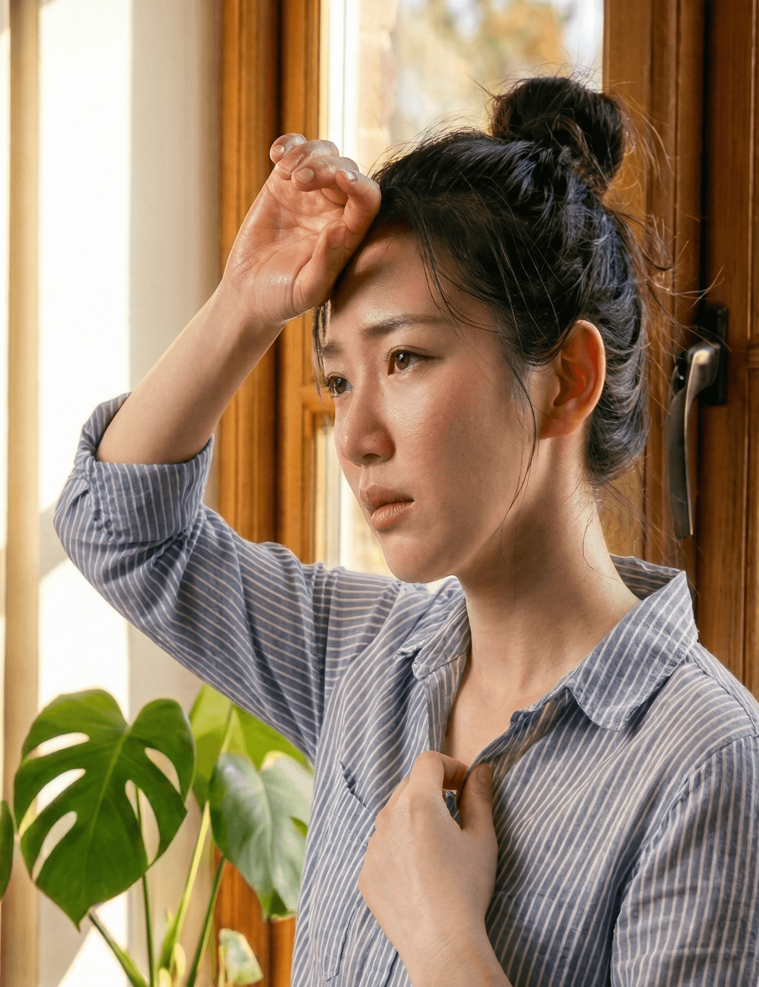 窓際で暑さに悩む女性